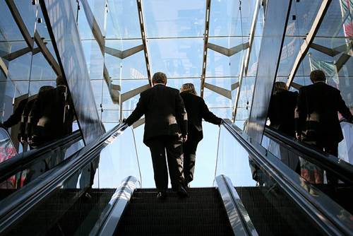 Two Executives at the Top of an Escalator in an Expensive Office Building