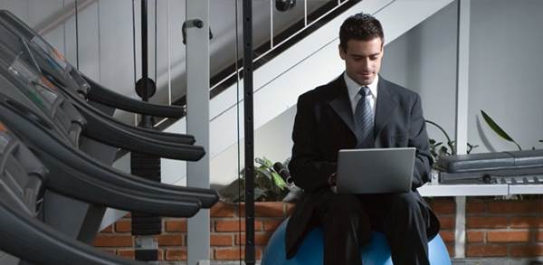 Executive Working in Office Alongside Gym Equipment