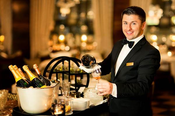 Hospitality Staff Member Pouring Champagne in a Glass